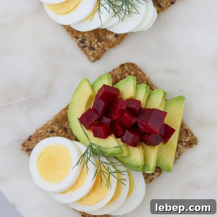 Toast with sliced egg, avocado and pickled beets on a plate