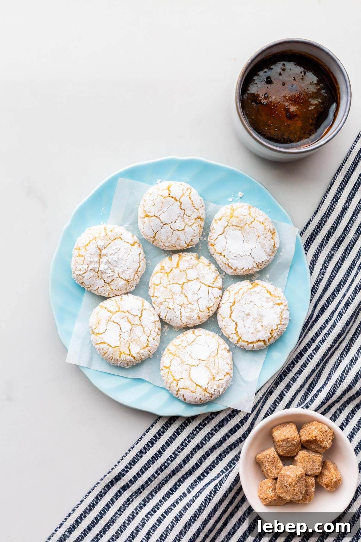 Orange Almond Amaretti Cookies Recipe — Zesty, Chewy Biscotti-Style Treats 2 A plate of amaretti cookies served with a cup of coffee.