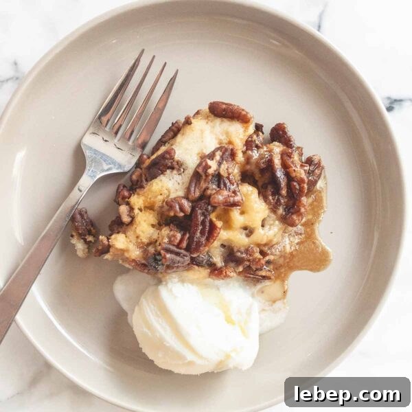 Pecan Pie Cobbler Recipe: Southern-Styled Gooey Pecan Dessert 11 A serving of pecan pie cobbler with a scoop of ice cream and a fork on the side.