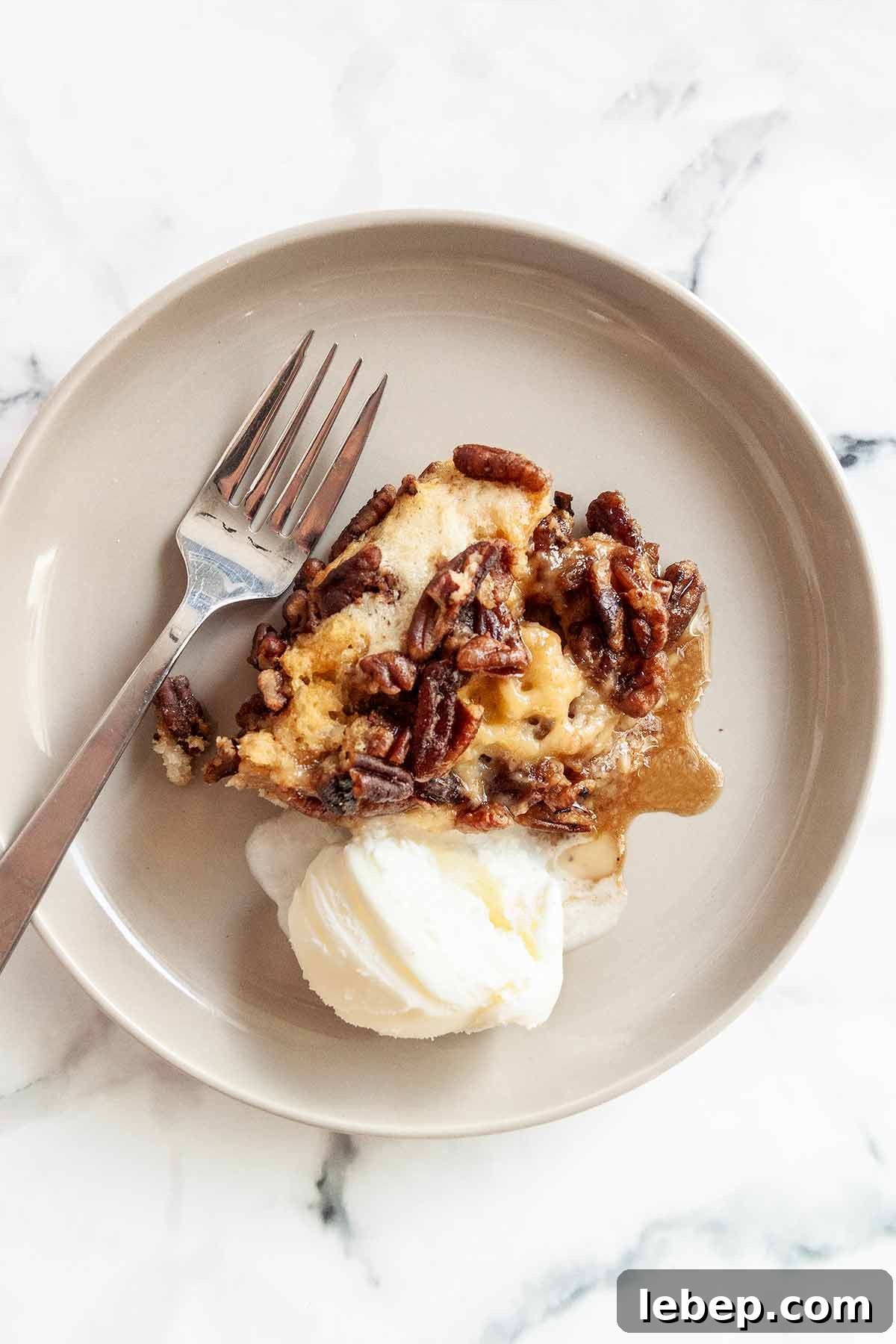 Pecan Pie Cobbler Recipe: Southern-Styled Gooey Pecan Dessert 8 A serving of pecan pie cobbler with a scoop of ice cream and a fork on the side.