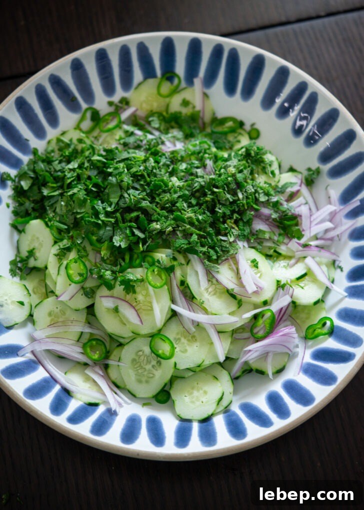 Sliced cucumber combined with herbs in a bowl.