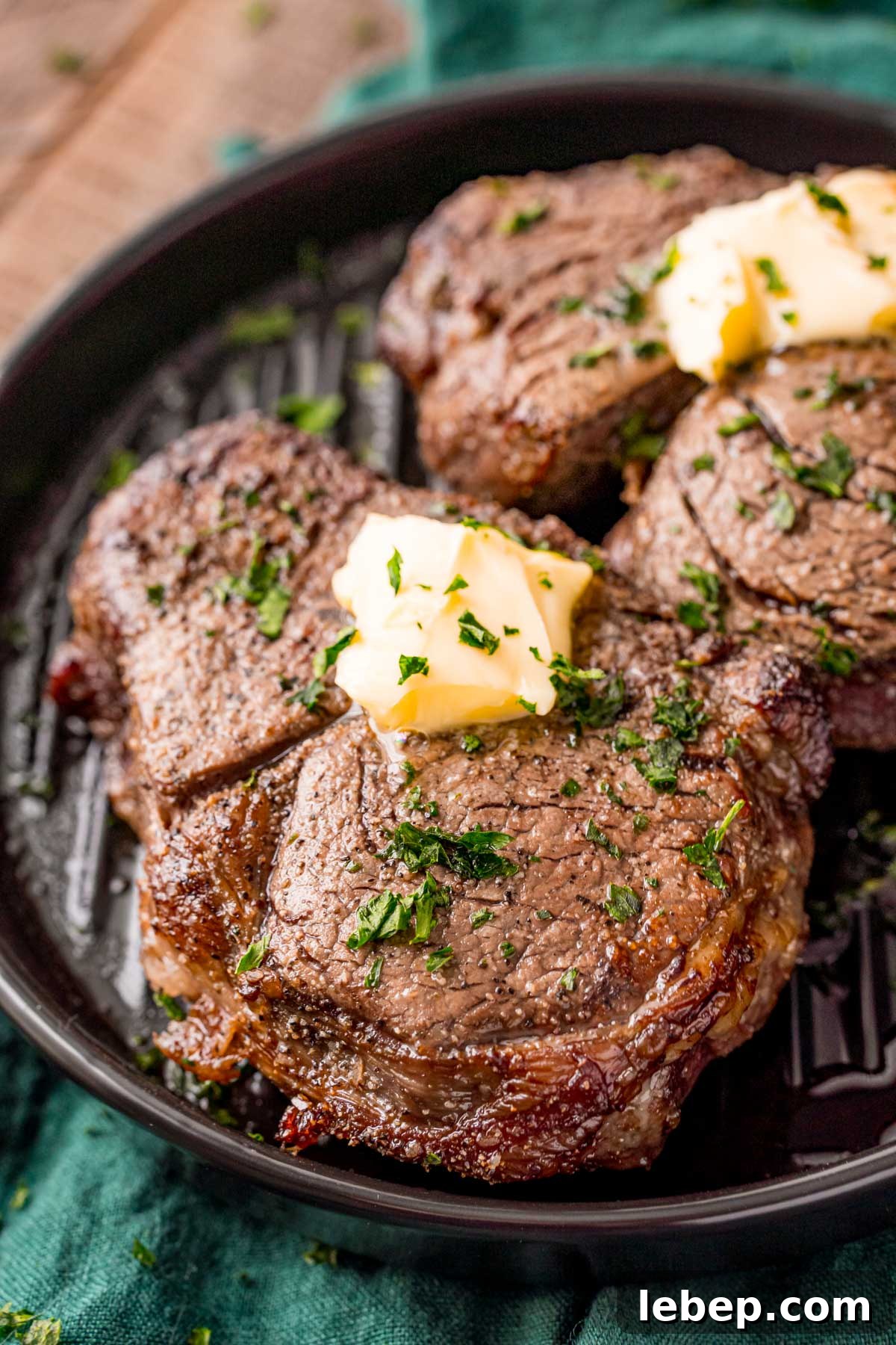 Perfect Air Fryer Filet Mignon Recipe for Tender Steak 2 Close up photo of air fryer filet mignon on a black plate on a green napkin.