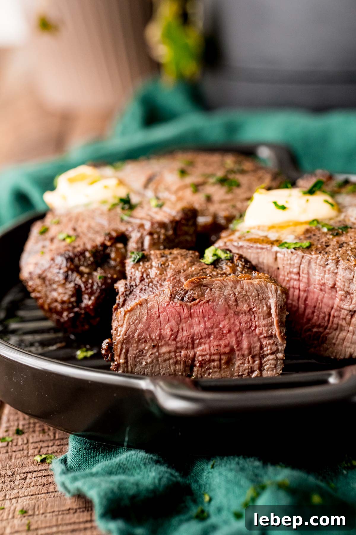 Perfect Air Fryer Filet Mignon Recipe for Tender Steak 3 Close up photo of a piece of steak sliced showing a pink center with the rest of the steak behind it on the plate.