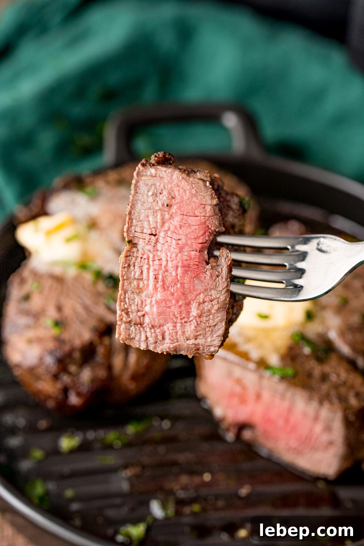 Perfect Air Fryer Filet Mignon Recipe for Tender Steak 6 A fork with a piece of steak on it being held towards the camera.