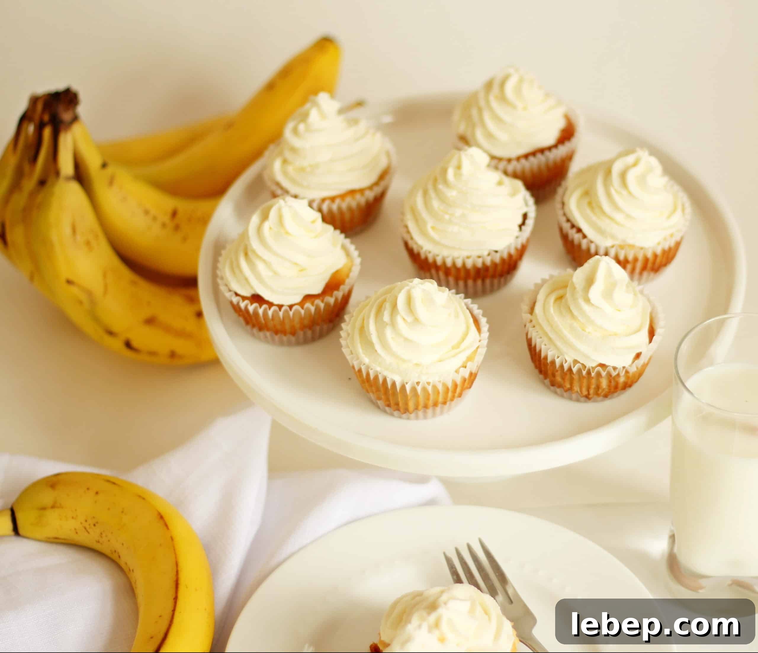 mini banana cheesecake on small dessert plate with another eight cheesecake on cake platter in the background