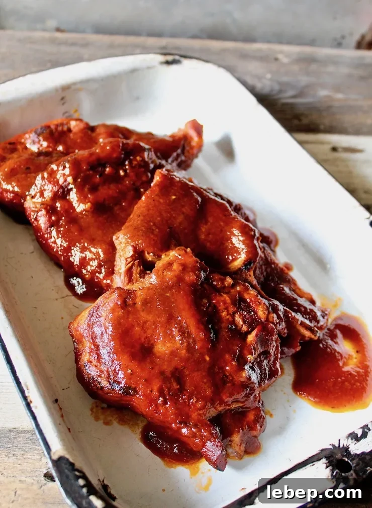 St. Louis Style BBQ Pork Steaks — Juicy Grilled Recipe 3 St. Louis BBQ Pork Steaks in a pan with sauce for serving.