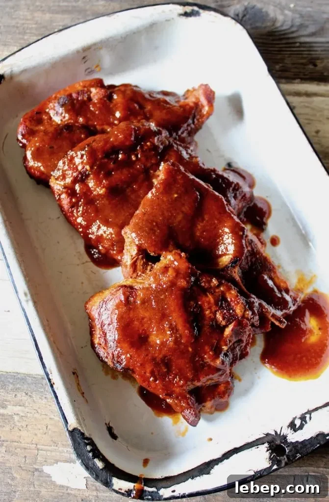 St. Louis Style BBQ Pork Steaks — Juicy Grilled Recipe 5 St. Louis BBQ Pork Steaks overhead shot in pan with sauce.