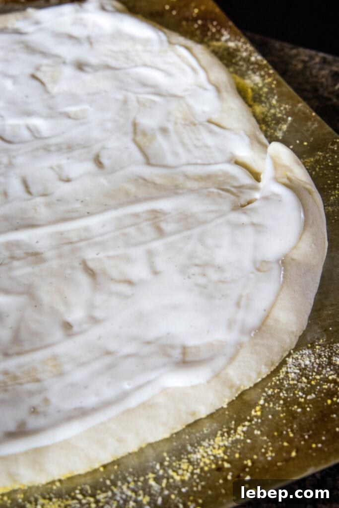 Ranch on pizza dough. Ranch dressing on top of pizza dough, on a cornmeal-covered baking sheet