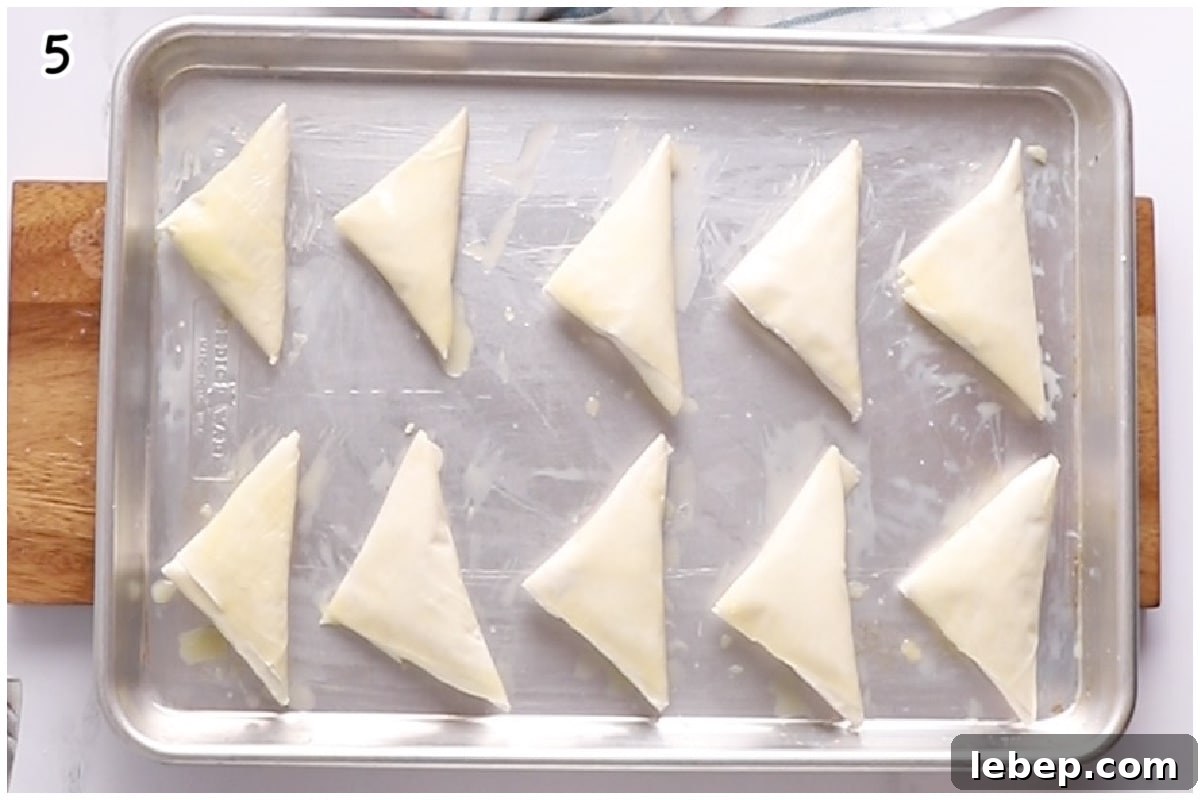 Finished spanakopita triangles on a tray.