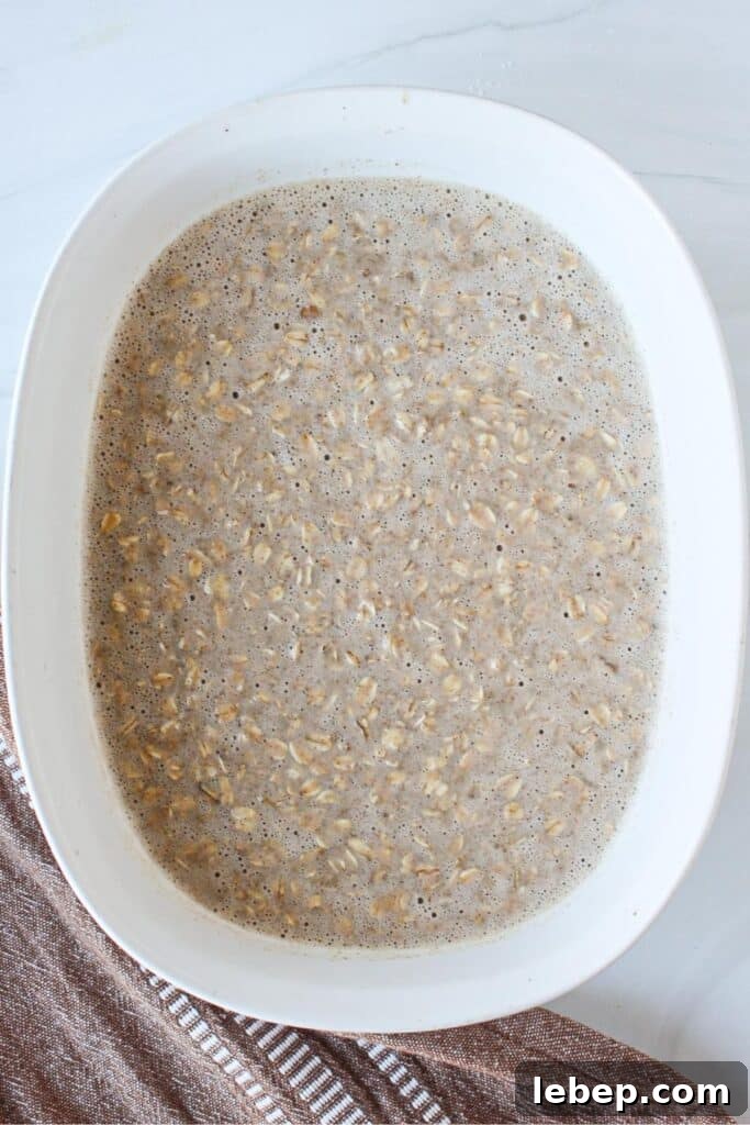 Cinnamon Roll Baked Oatmeal — Morning Bake with Creamy Glaze 6 A casserole dish of oats, eggs, bananas and other ingredients ready to go into the oven.