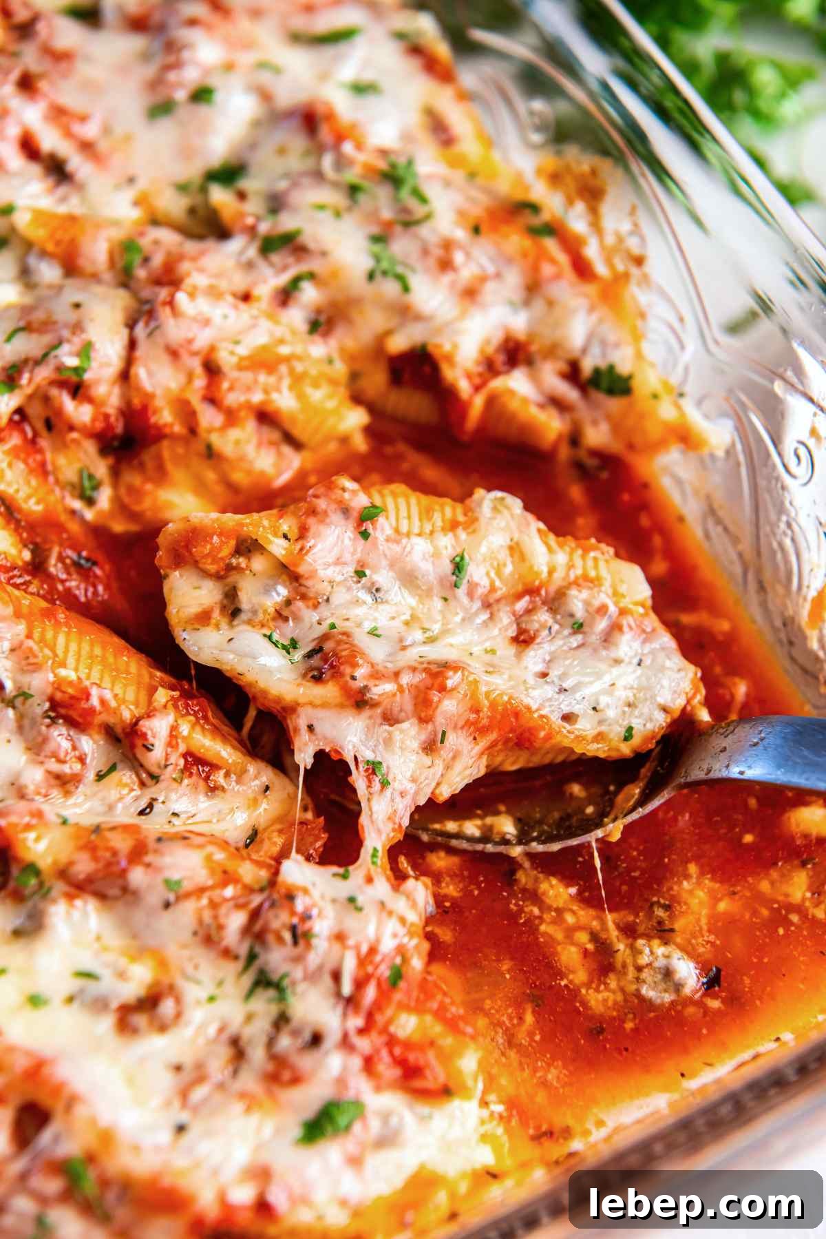 Baked Stuffed Shells with Beef and Cottage Cheese Filling 2 Stuffed shell with ground beef filling lifted from baking dish showing melted cheese and marinara sauce