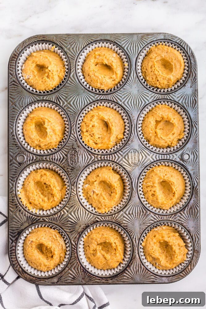 Fluffy Pumpkin Muffins with Cream Cheese Swirl 13 picture of pumpkin batter in muffin tin with indents in the tops