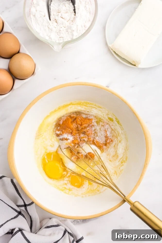Fluffy Pumpkin Muffins with Cream Cheese Swirl 7 picture of pumpkin batter being mixed in a bowl