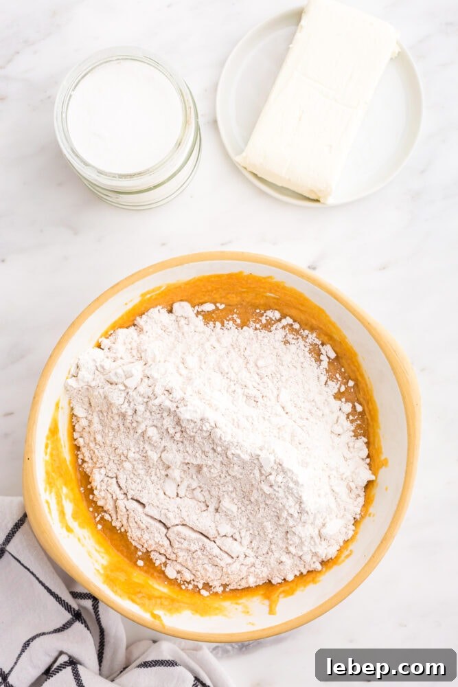 Fluffy Pumpkin Muffins with Cream Cheese Swirl 9 picture of flour and pumpkin puree being mixed in a bowl