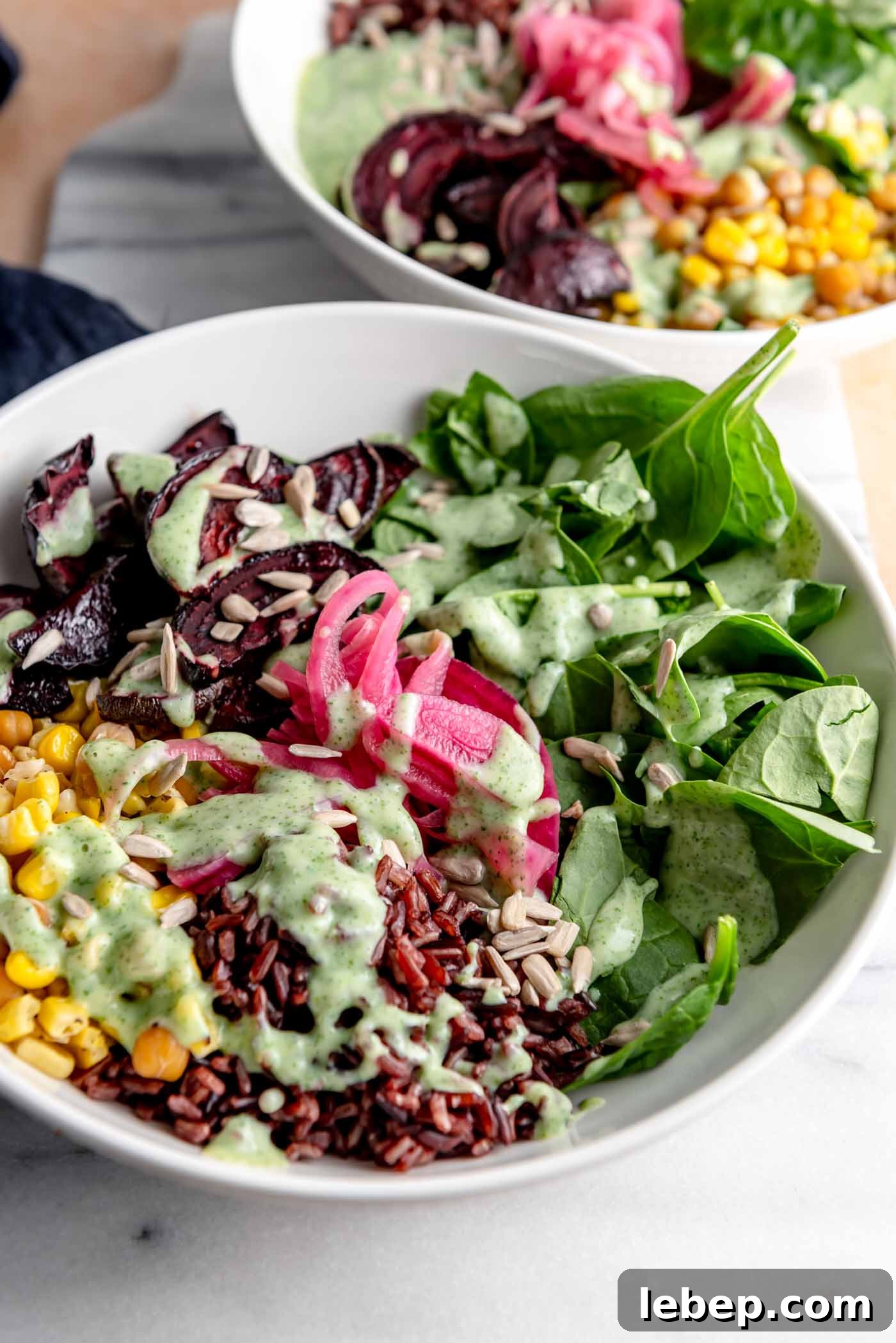 Wild rice bowl with chickpeas, spinach, pickled onion, corn and chickpeas on a marble cutting board. A second bowl is shown in the background.