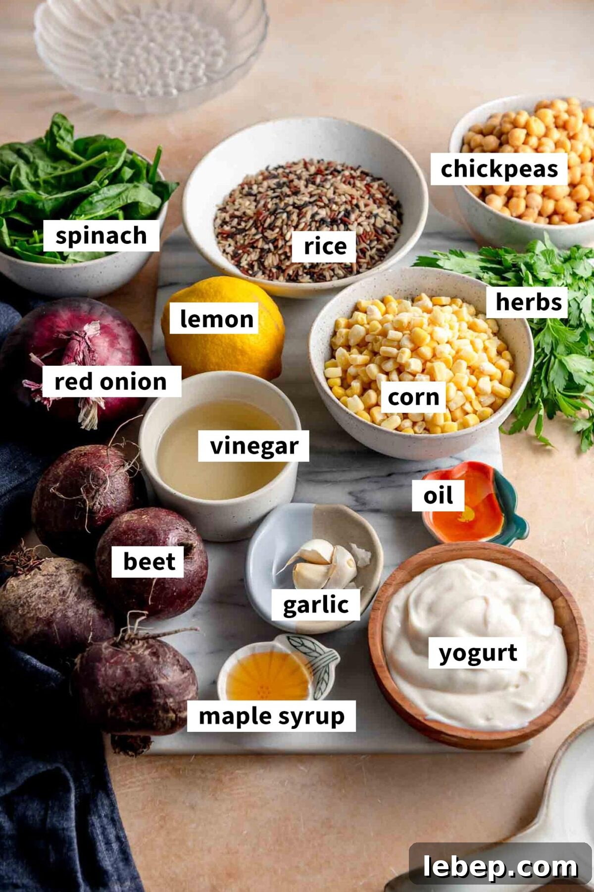 All the ingredients gathered in various bowls on a cutting board for making a wild rice bowl with chickpeas, corn, yogurt dressing and spinach.