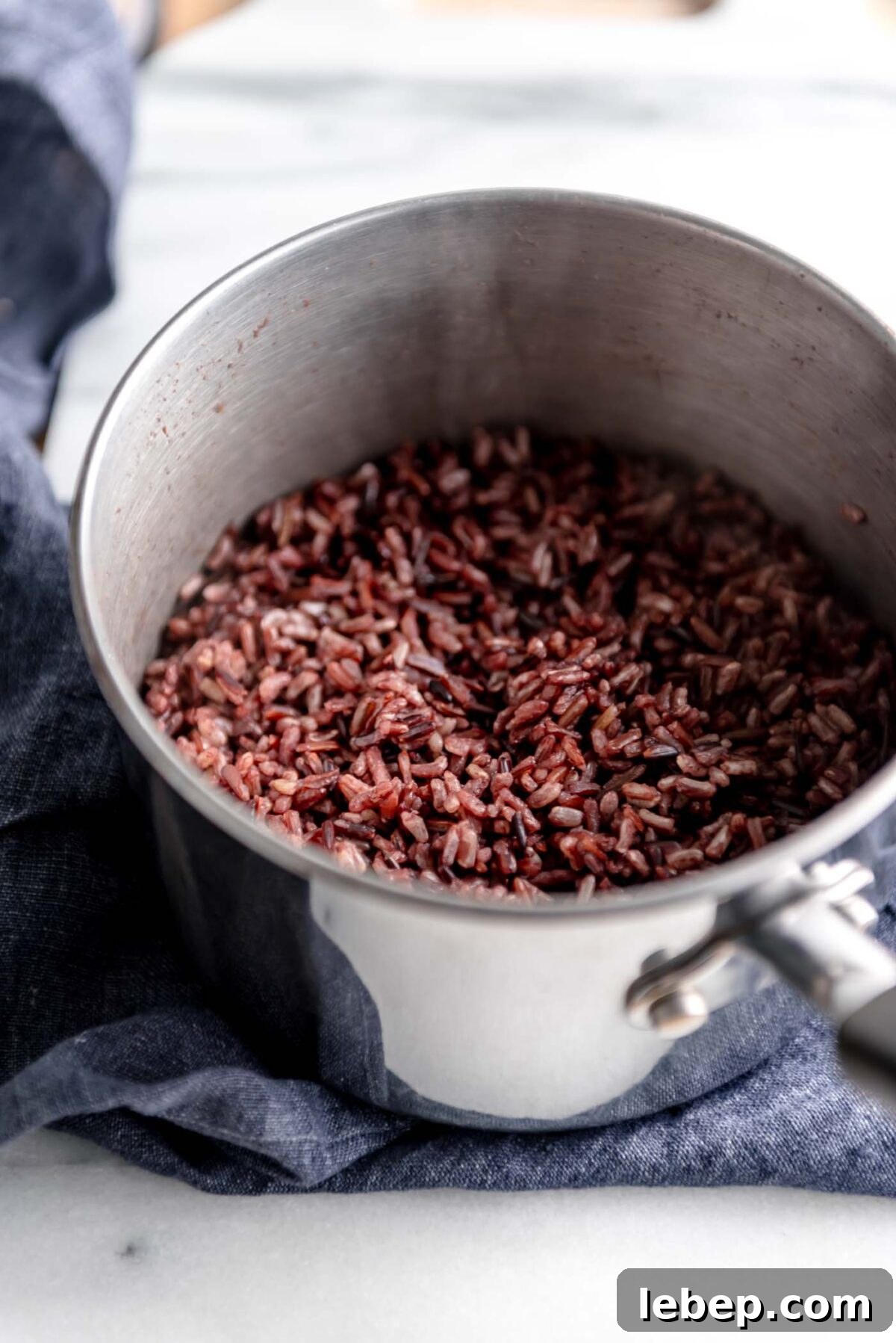 Cooked wild rice in a pot on a marble cutting board.