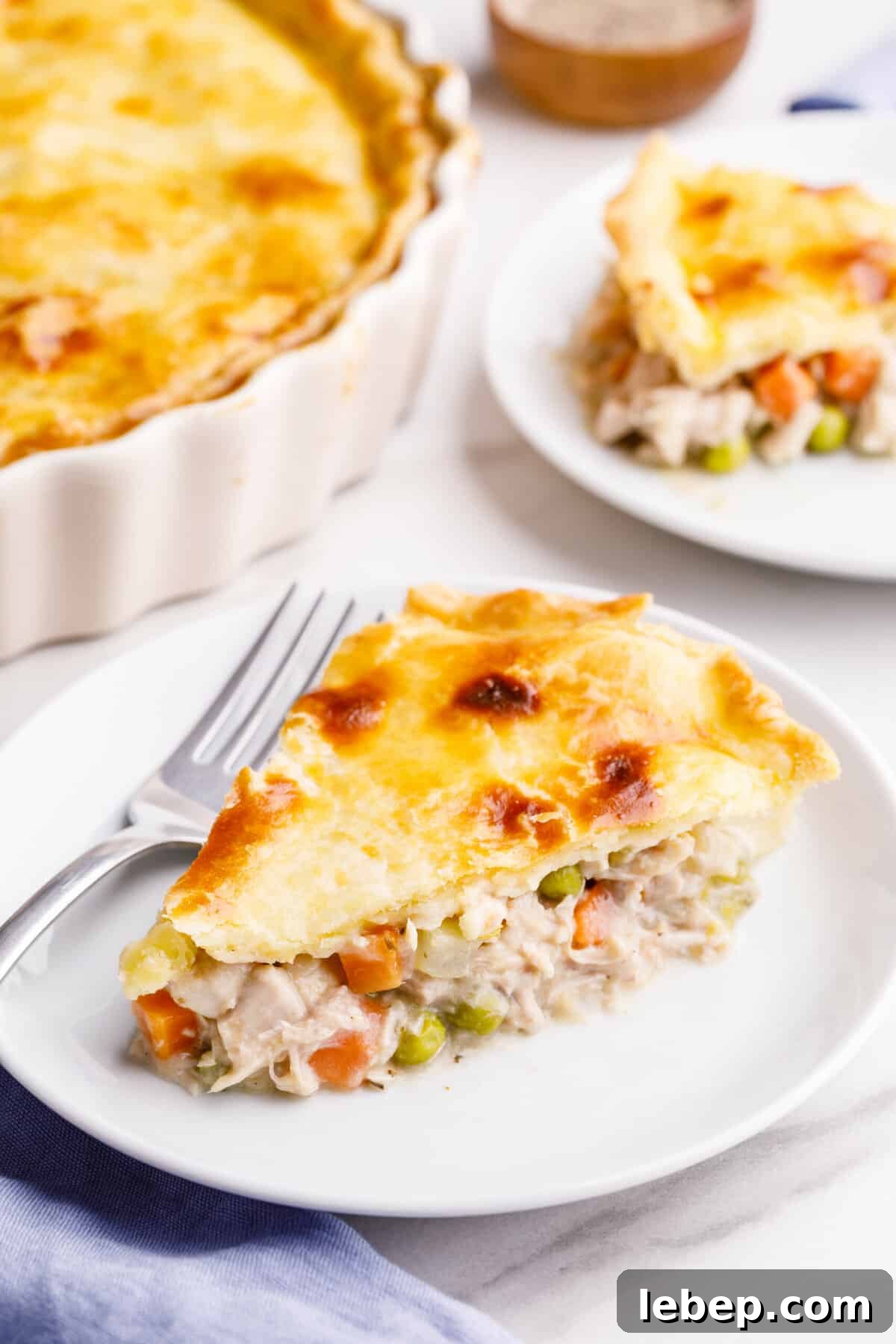 Comfortable Turkey Pot Pie Recipe with Flaky Crust 2 slice of turkey pot pie served on a white round plate with a silver fork