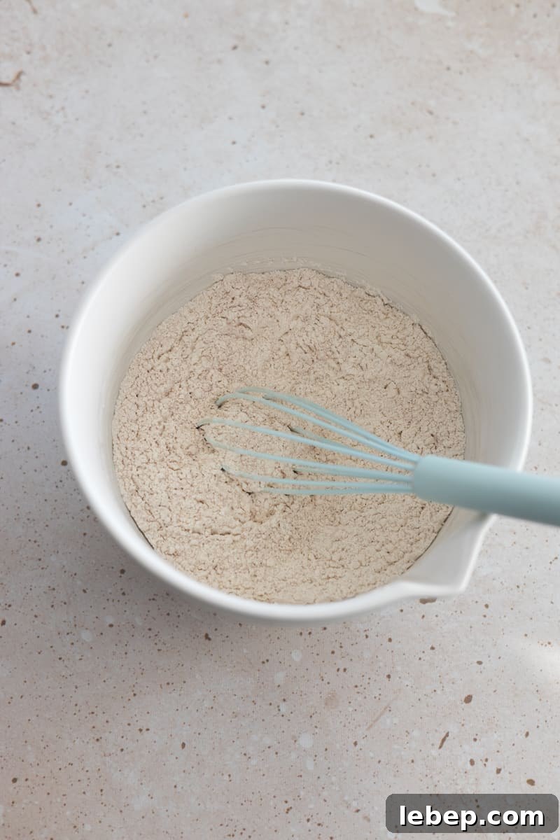 Dry ingredients in a white bowl with a whisk.