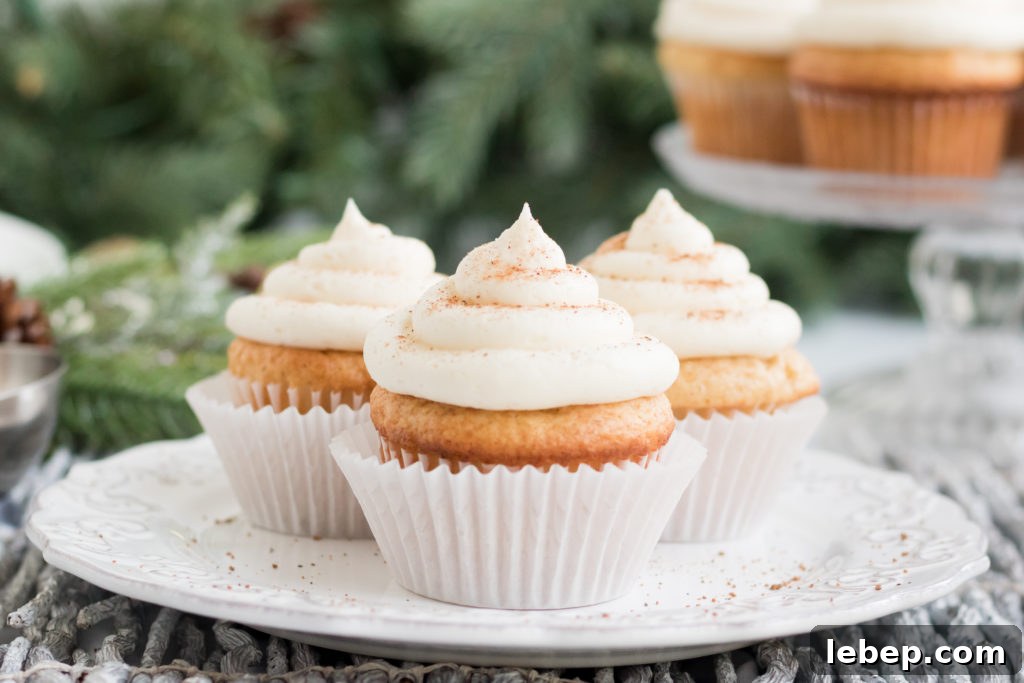 Eggnog Cupcakes Recipe with Spiced Rum Glaze 2 Three vanilla cupcakes on a plate with a garland in the background