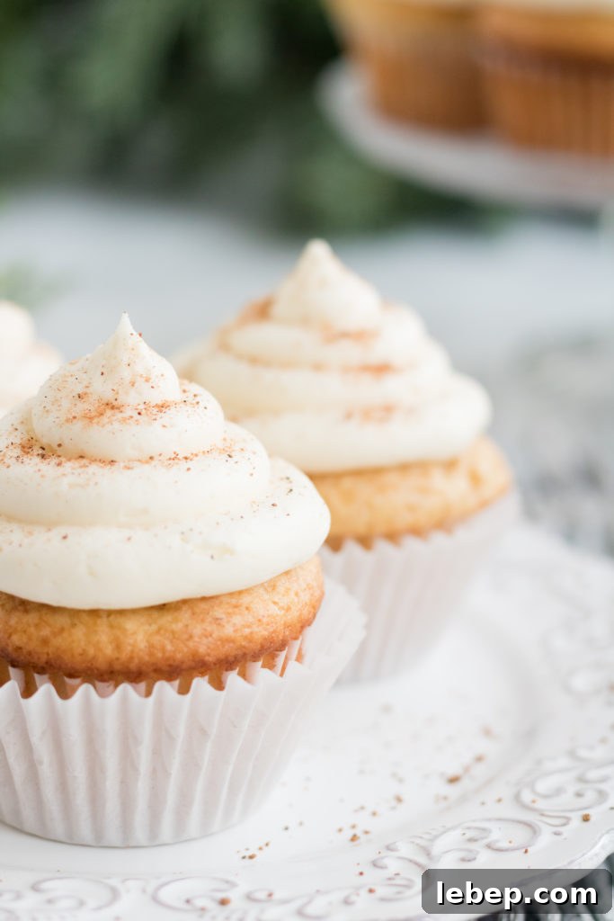 Eggnog Cupcakes Recipe with Spiced Rum Glaze 8 Egg nog cupcake- a close up shot of an egg nog cupcake with a white cupcake liner on a white plate.