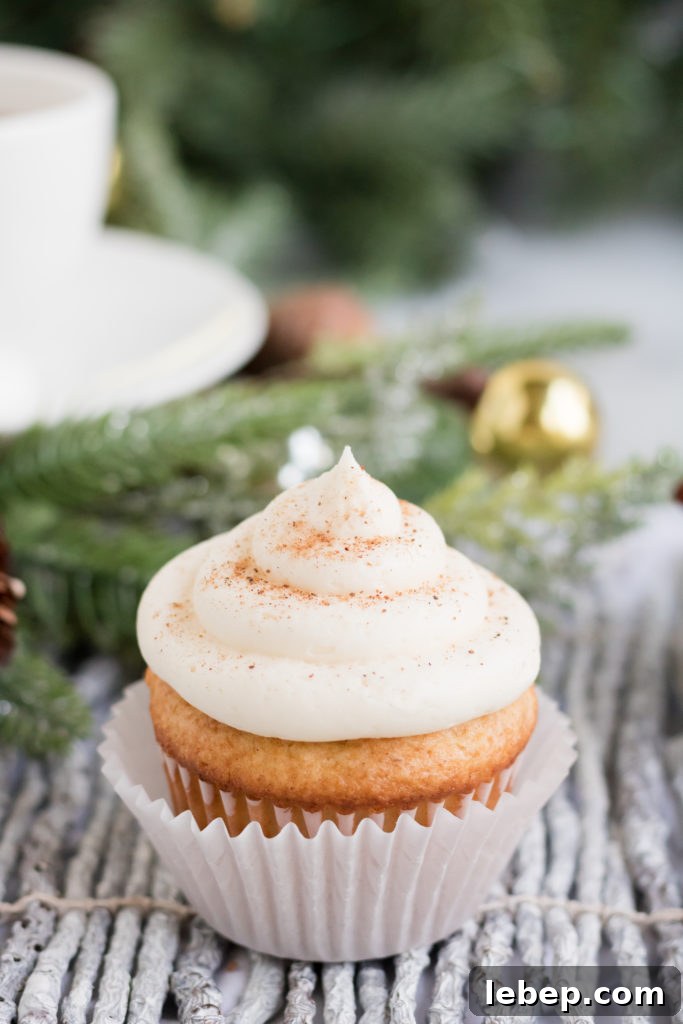 Eggnog Cupcakes Recipe with Spiced Rum Glaze 9 A single eggnog cupcake sits on a birchwood placemat with a garland behind it.