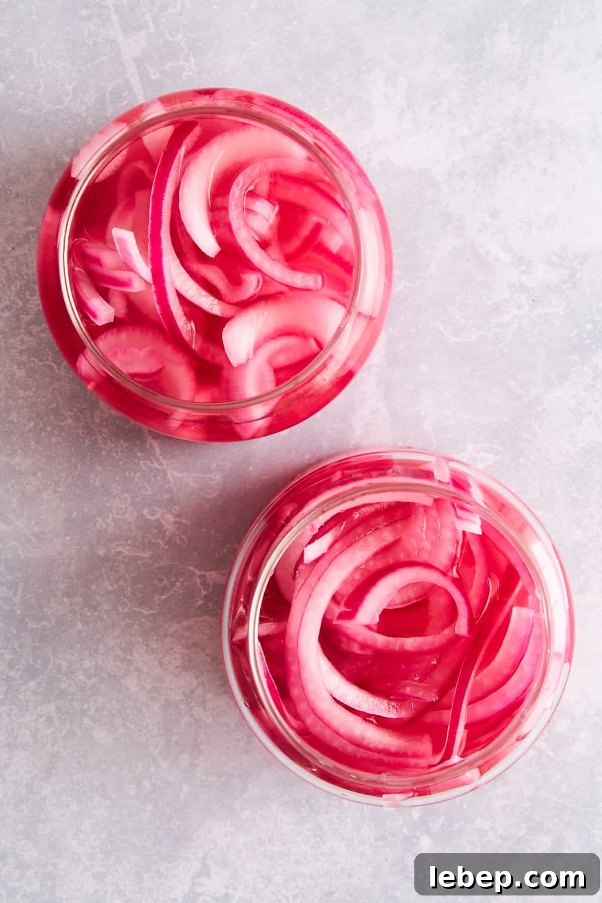 Overhead image of two jars of pickled red onions. 