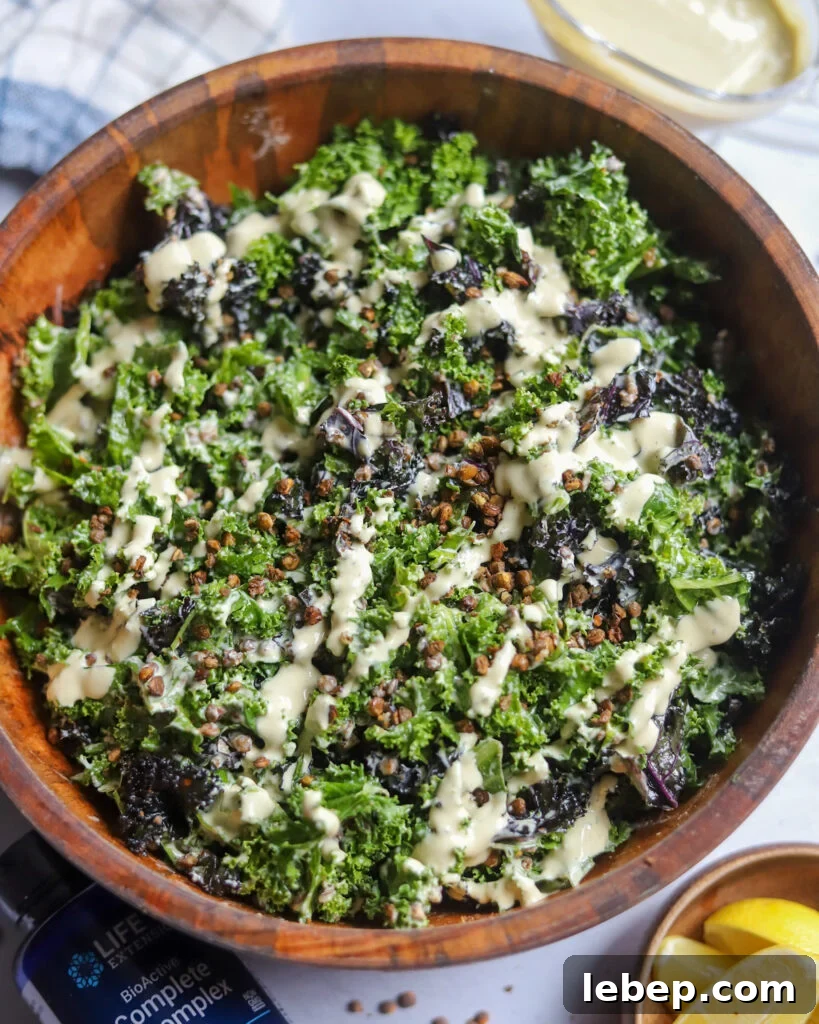 overhead view of a wooden bowl with homemade vegan caesar with lentils, kale, and a tangy tofu dressing next to lemons and a bottle of b vitamins.