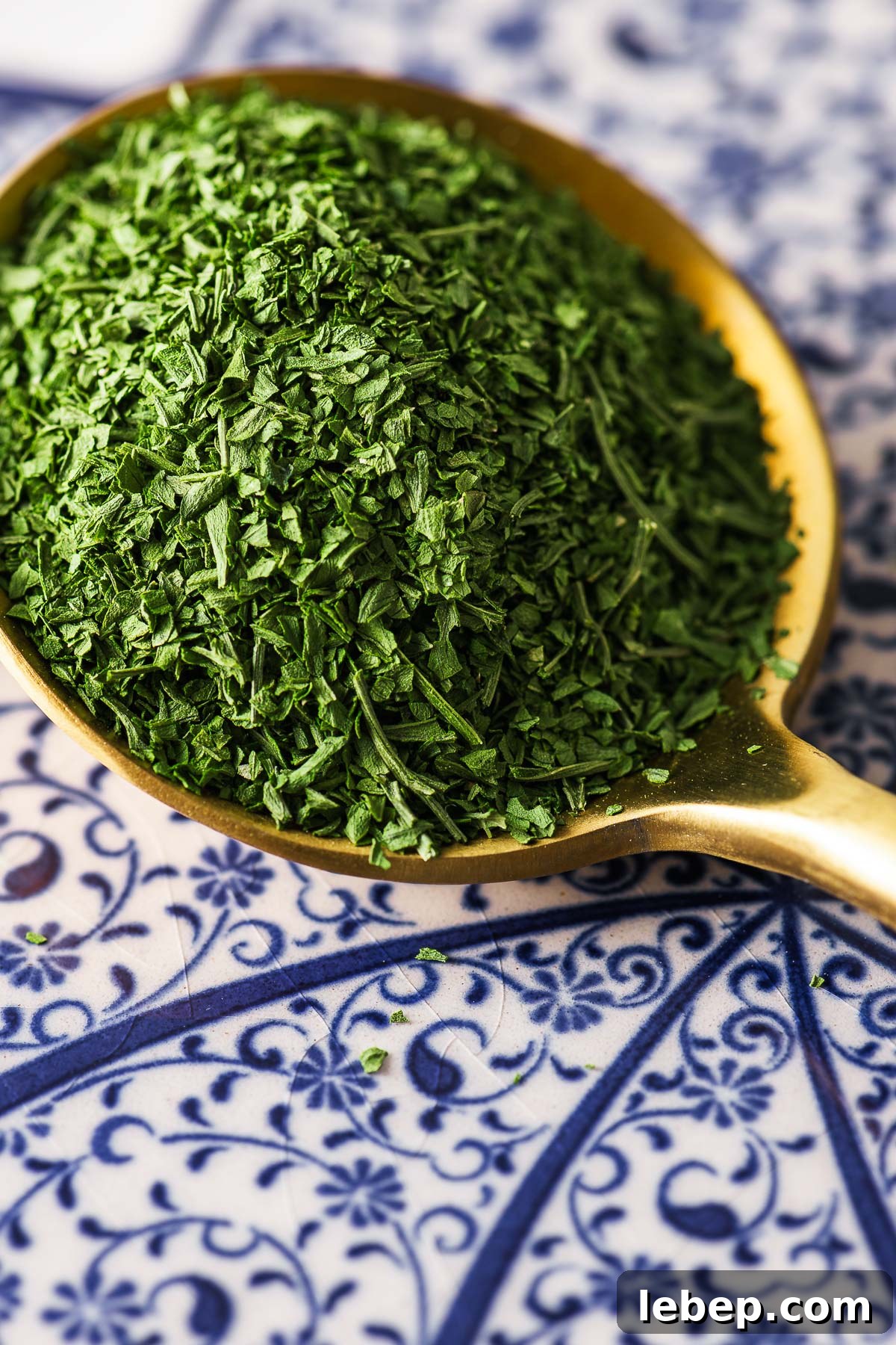 Drying Parsley in the Oven: Quick Guide for Flavorful Dried Herbs 3 A close-up of a tablespoon of dried parsley on a patterned background.