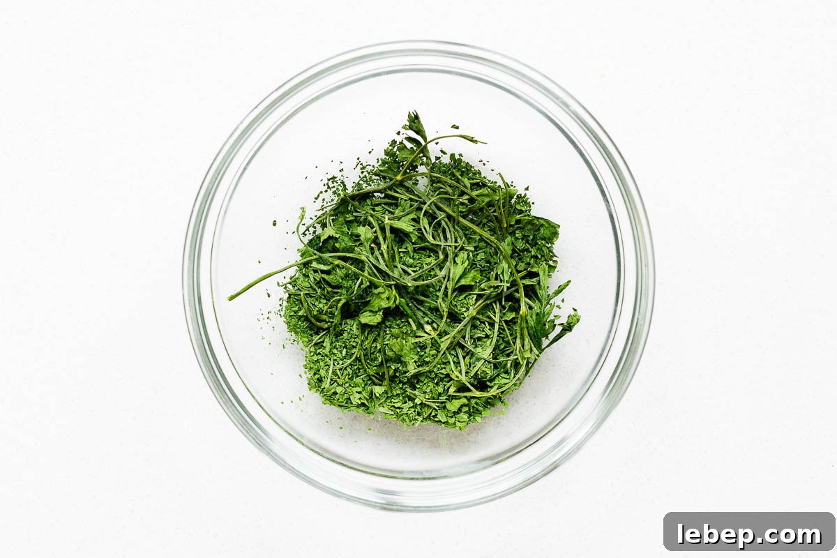 Drying Parsley in the Oven: Quick Guide for Flavorful Dried Herbs 8 Roughly crumbled oven dried parsley with stems in a glass bowl.