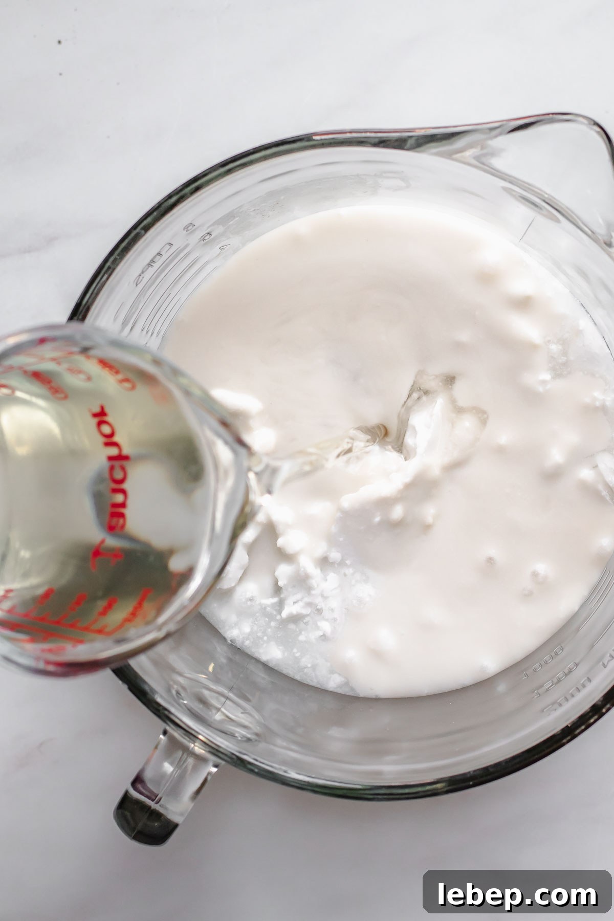 Creamy Coconut Sorbet Recipe: Refreshing Tropical Dessert 5 Coconut simple syrup pouring into coconut milk.