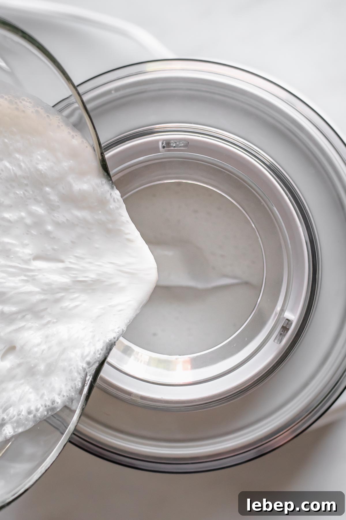 Creamy Coconut Sorbet Recipe: Refreshing Tropical Dessert 7 Coconut mixture being poured into an ice cream machine.