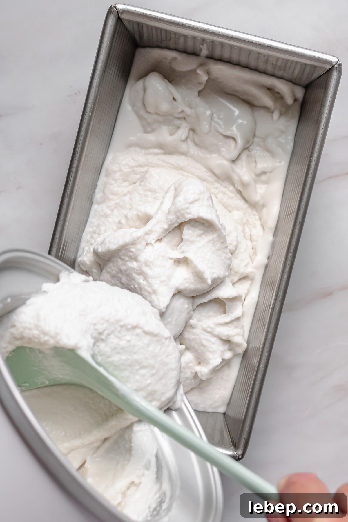 Creamy Coconut Sorbet Recipe: Refreshing Tropical Dessert 10 Coconut sorbet being poured into a pan to freeze.