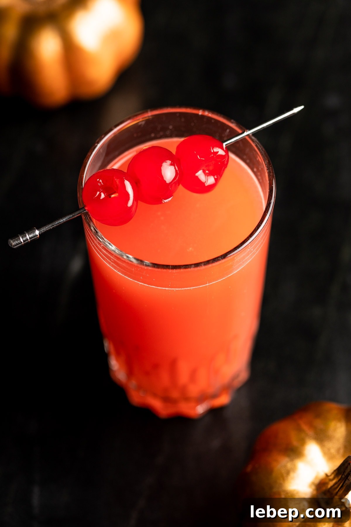 How to Make a Red Devil Cocktail: Recipe & Serving Tips 6 Red devil drink garnished with maraschino cherries, on a black marble table.