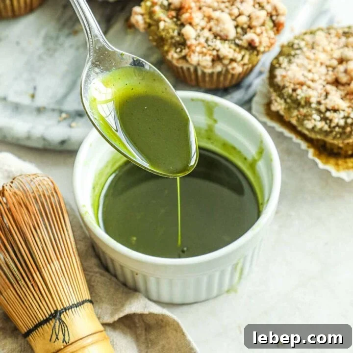 Spoon pouring matcha vanilla bean glaze for cakes, muffins, quick breads, and more in a white ceramic ramekin.