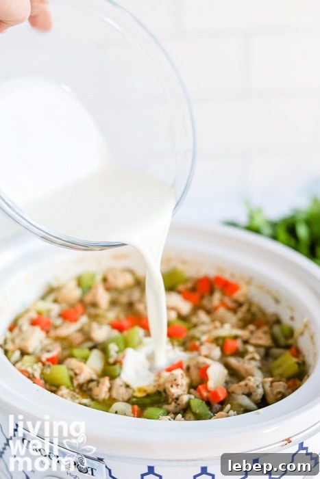 Creamy Slow Cooker Wild Rice and Chicken Soup Recipe 8 Pouring cream into creamy chicken and wild rice soup in the slow cooker