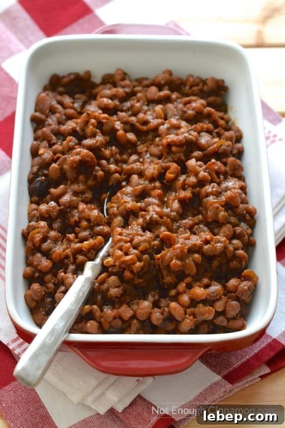 overhead shot of a red casserole filled with homemade slow cooker baked beans with molasses, bacon and brown sugar