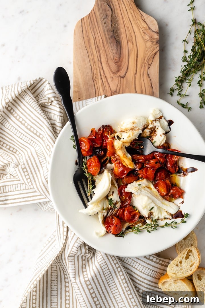 A winter Caprese salad with roasted tomatoes plated with two forks, for sharing!