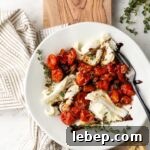 A white plate with a roasted tomato winter Caprese salad on it.