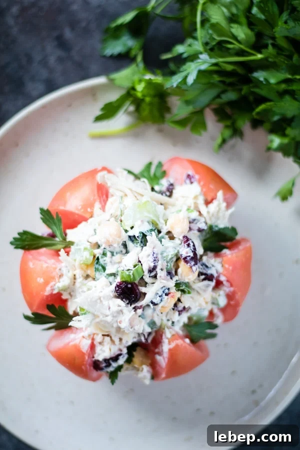 Greek Yogurt Chicken Salad Served in Tomato Wedges 2 Mayo free Chicken salad stuffed inside of a heirloom tomato on a plate with parsley on the side.