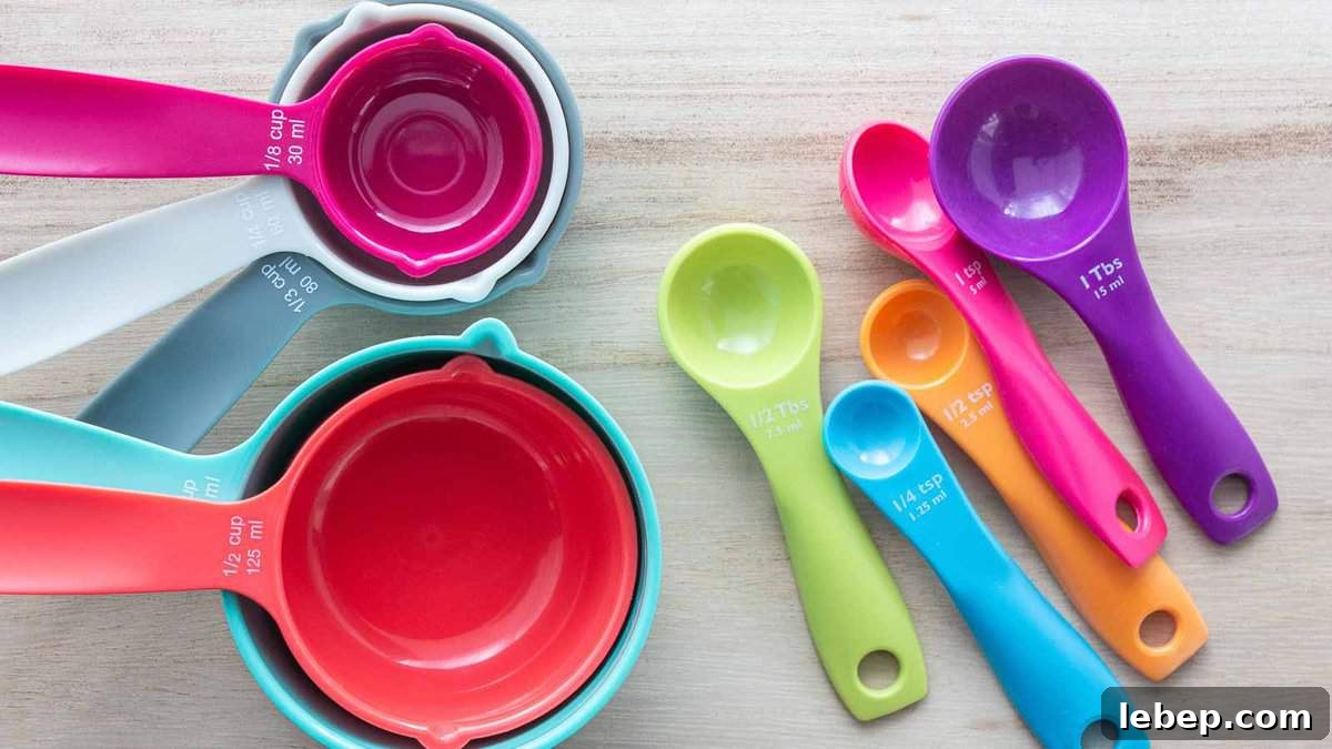 Cooking Measurement Guide: Key Conversions for Accurate Results 4 A set of colorful measuring cups and spoons arranged on a wooden surface. The cups and spoons range in size and are vibrant in colors such as pink, orange, green, blue, and purple.
