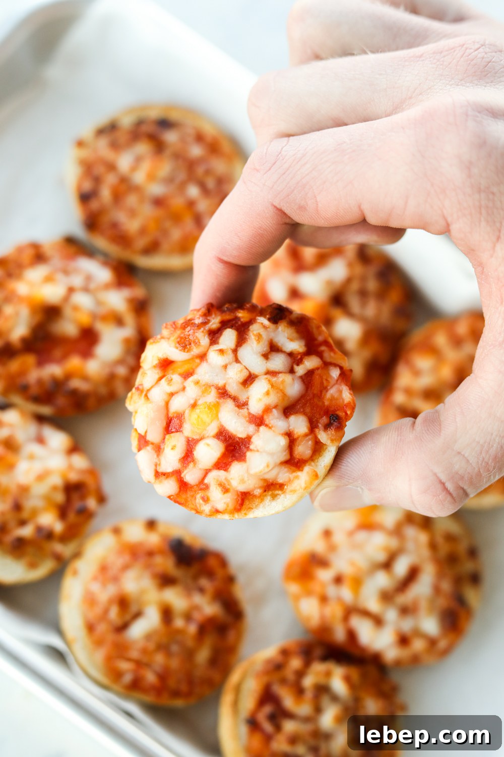 Air Fryer Bagel Bites: Quick Crispy Snack in Minutes 7 Hand holding a pizza bagel above other bagels
