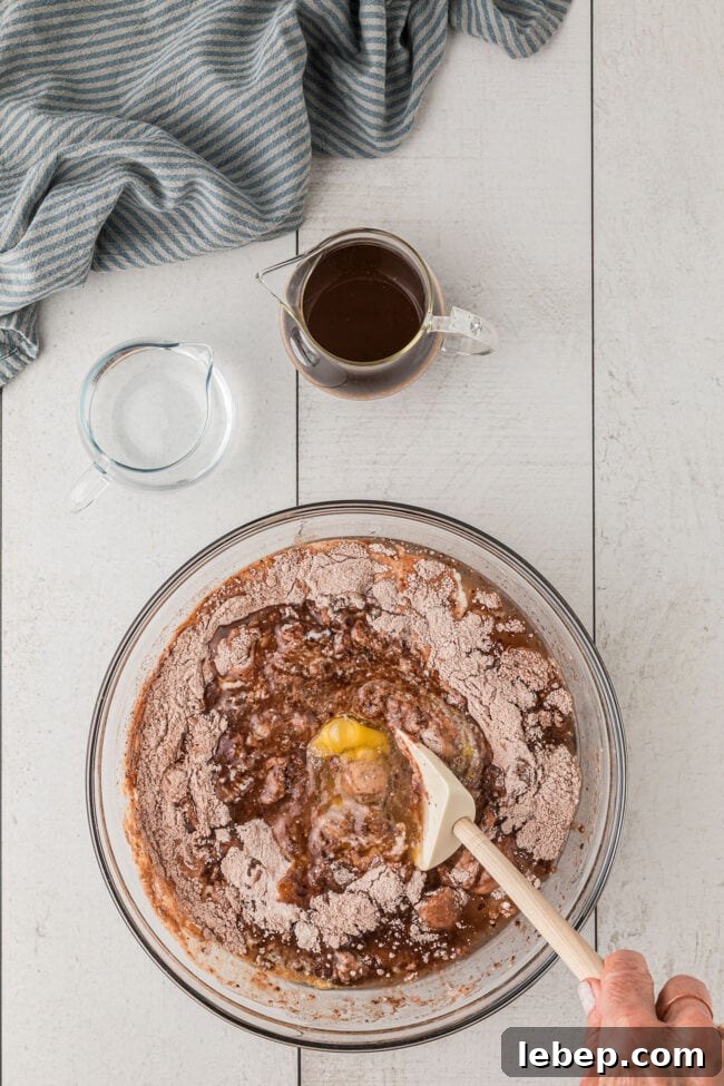 Ultra-Rich One-Bowl Chocolate Cake Recipe You’ll Love 5 mixing chocolate cake wet ingredients in a clear mixing bowl.