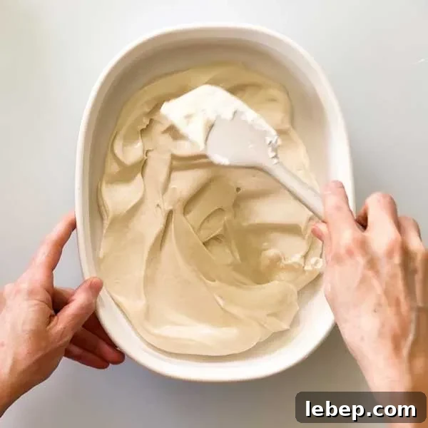 Spreading the peach pie cottage cheese ice cream in a shallow dish with a spatula.