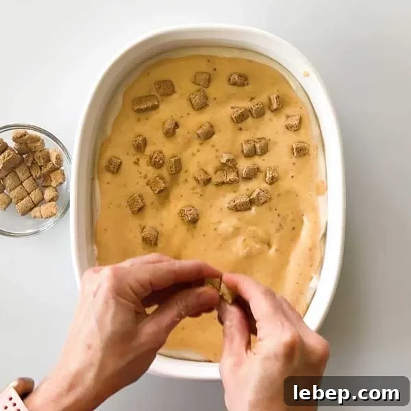 Sprinkling graham cracker bits over the peach ice cream layer in the dish.