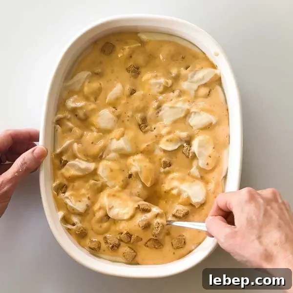 Gently folding in all the peach pie ice cream ingredients in the dish with a spoon.