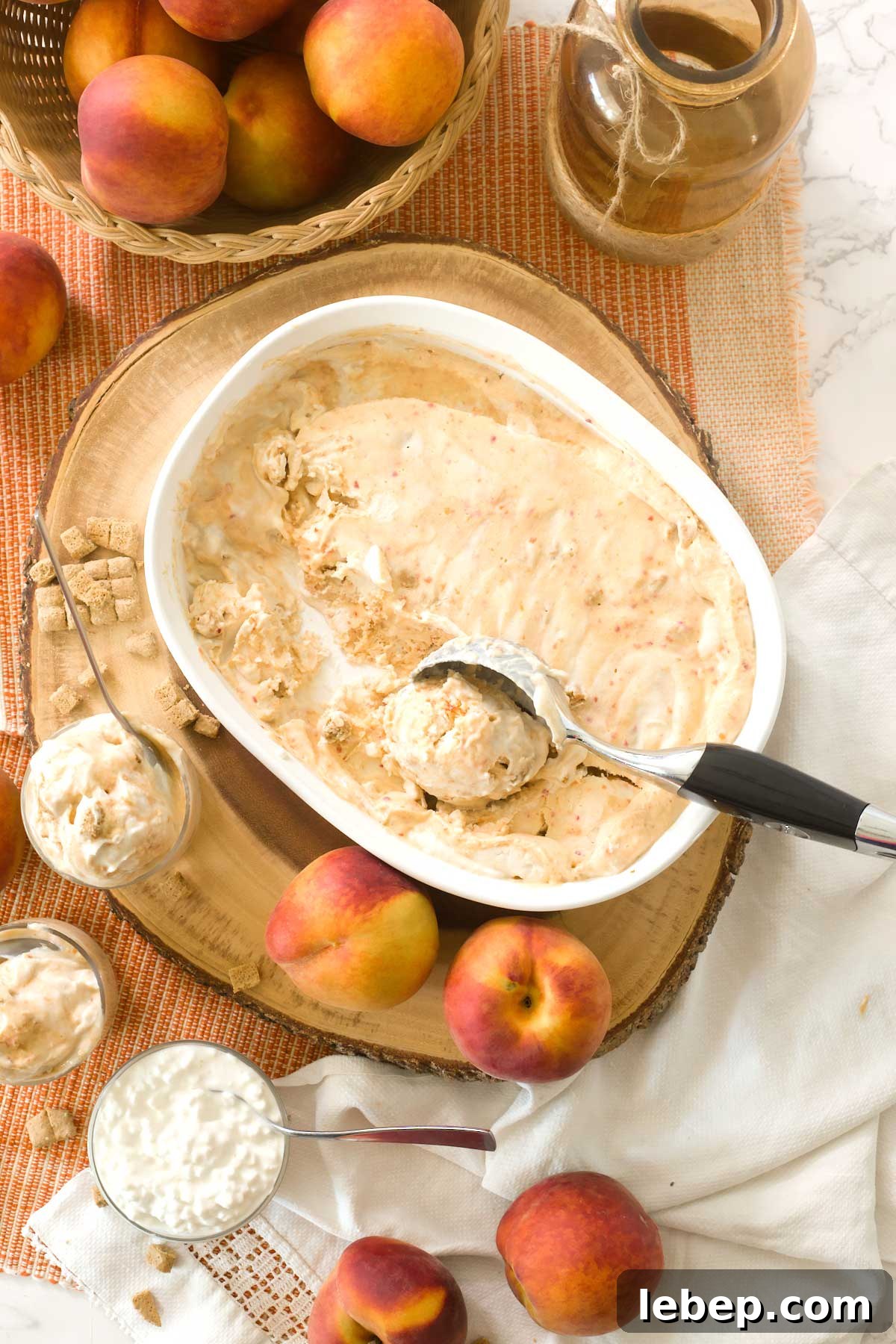 The top view of a white dish with gluten-free peach pie cottage cheese ice cream and an ice cream scoop.