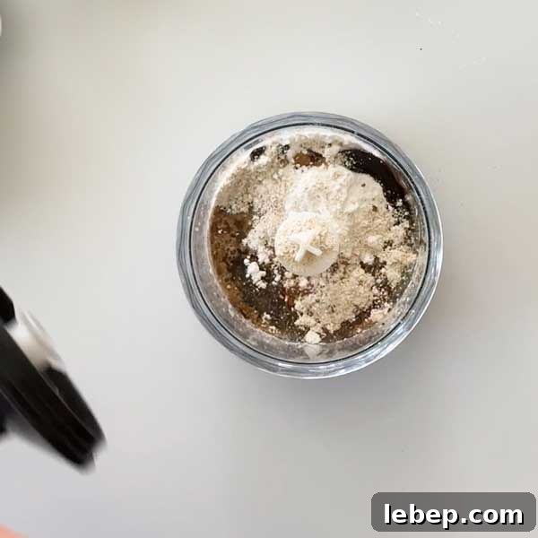 Adding the ingredients to the chopper cup with an immersion blender.