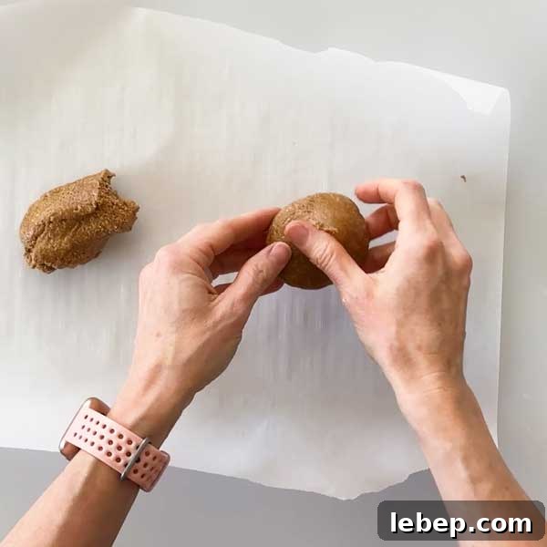 Rolling the graham cracker batter in a ball over a parchment paper.