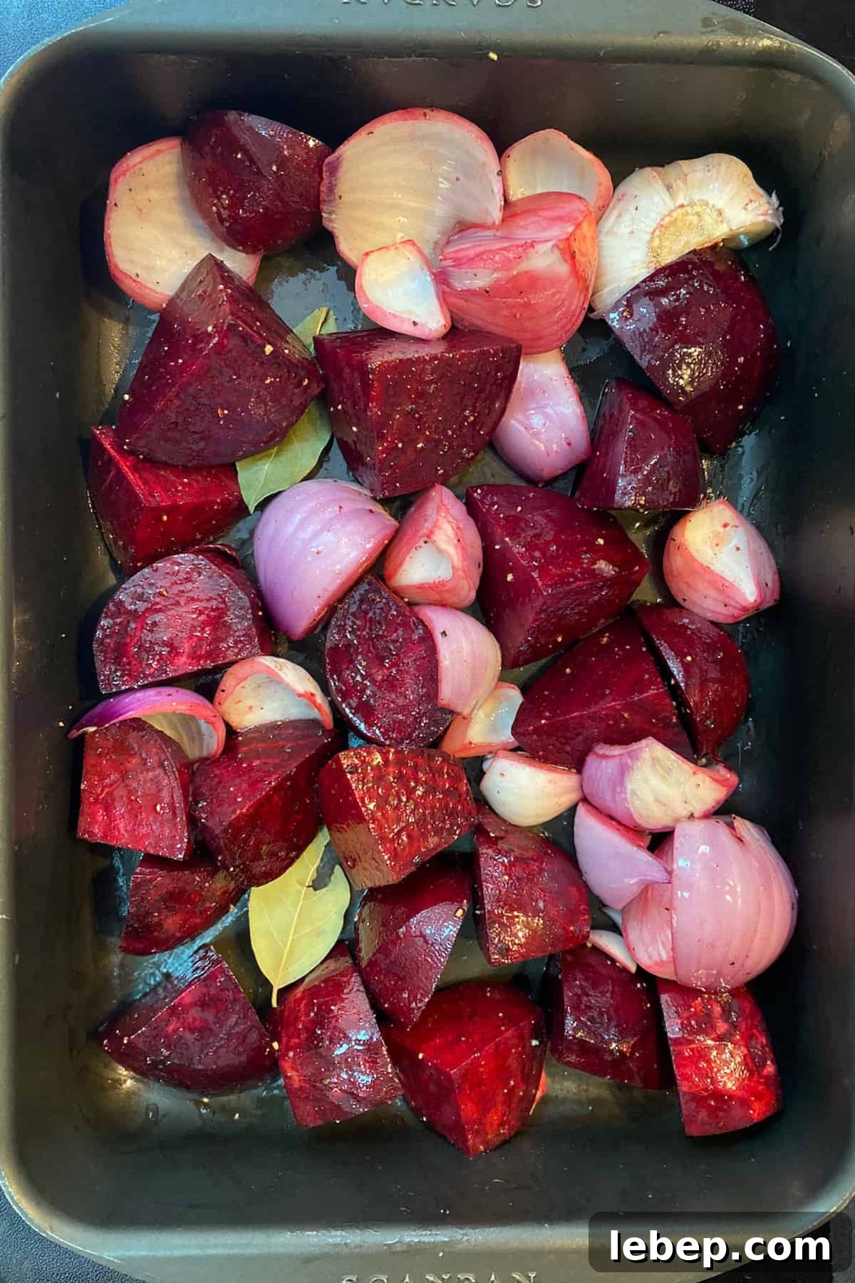 Photo of chopped beetroots, red onions and garlic in a roasting tin ready to go in the oven.